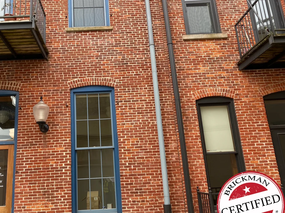 The front of the downtown Michigan building in 2020, one range of red brick around arched windows with blue frames, iron balconies above.