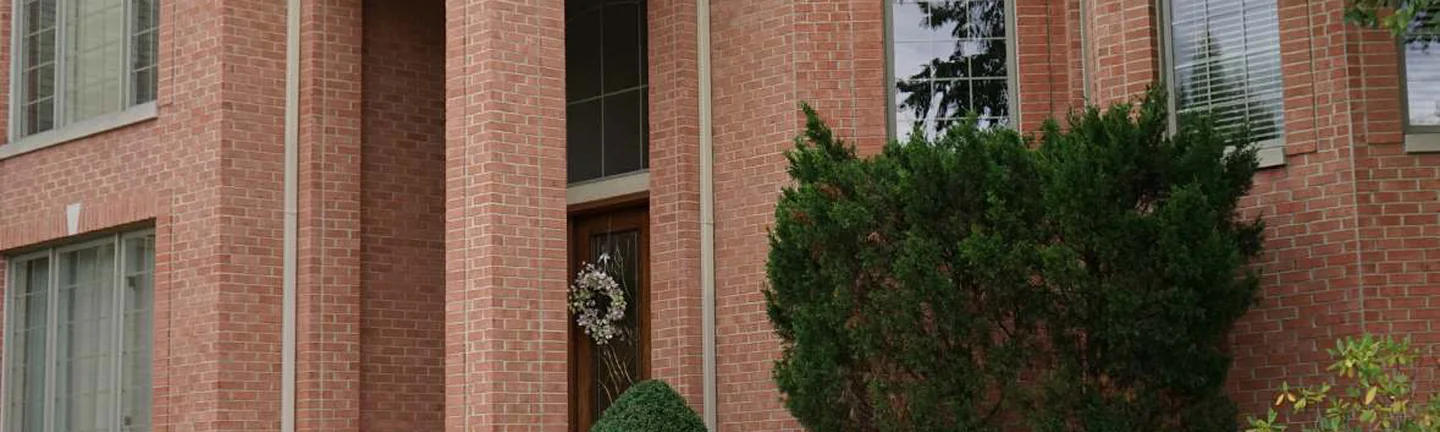 Red brick across the front of the house in 2019, cast stone arches over the entry and a tall arched window beside it