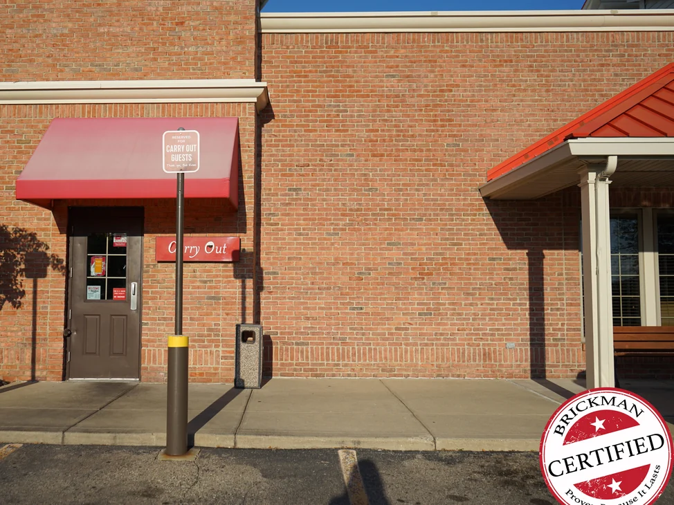 The carry out entrance and the long brick wall beside it in 2019, the brick one even red and brown range from the awning to the porch at the far end.