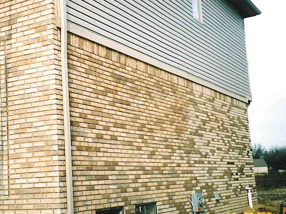 An outside corner during the 2003 work, a ladder against the near face and the return wall carrying warm tan color over the pale brick