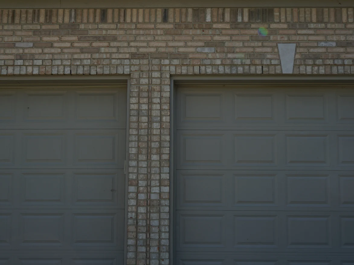 Two garage doors with a stained brick pier between them, a soldier course and a cast keystone running above the openings