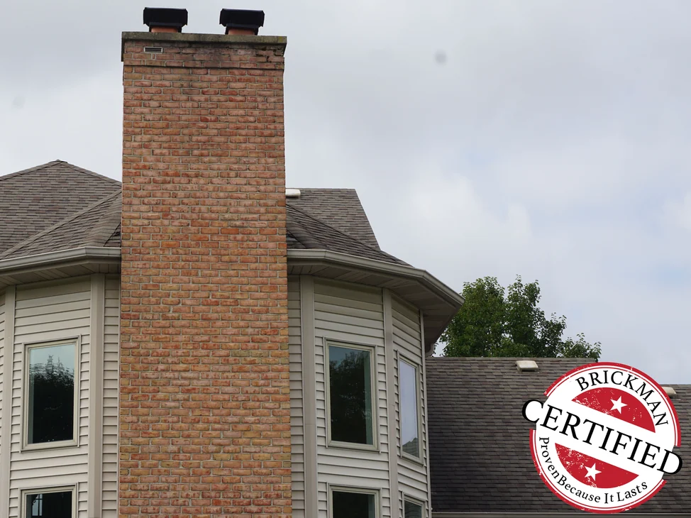 The chimney in 2019 running past the bay window and the roof to its cap, the brick one warm red and tan range the whole height