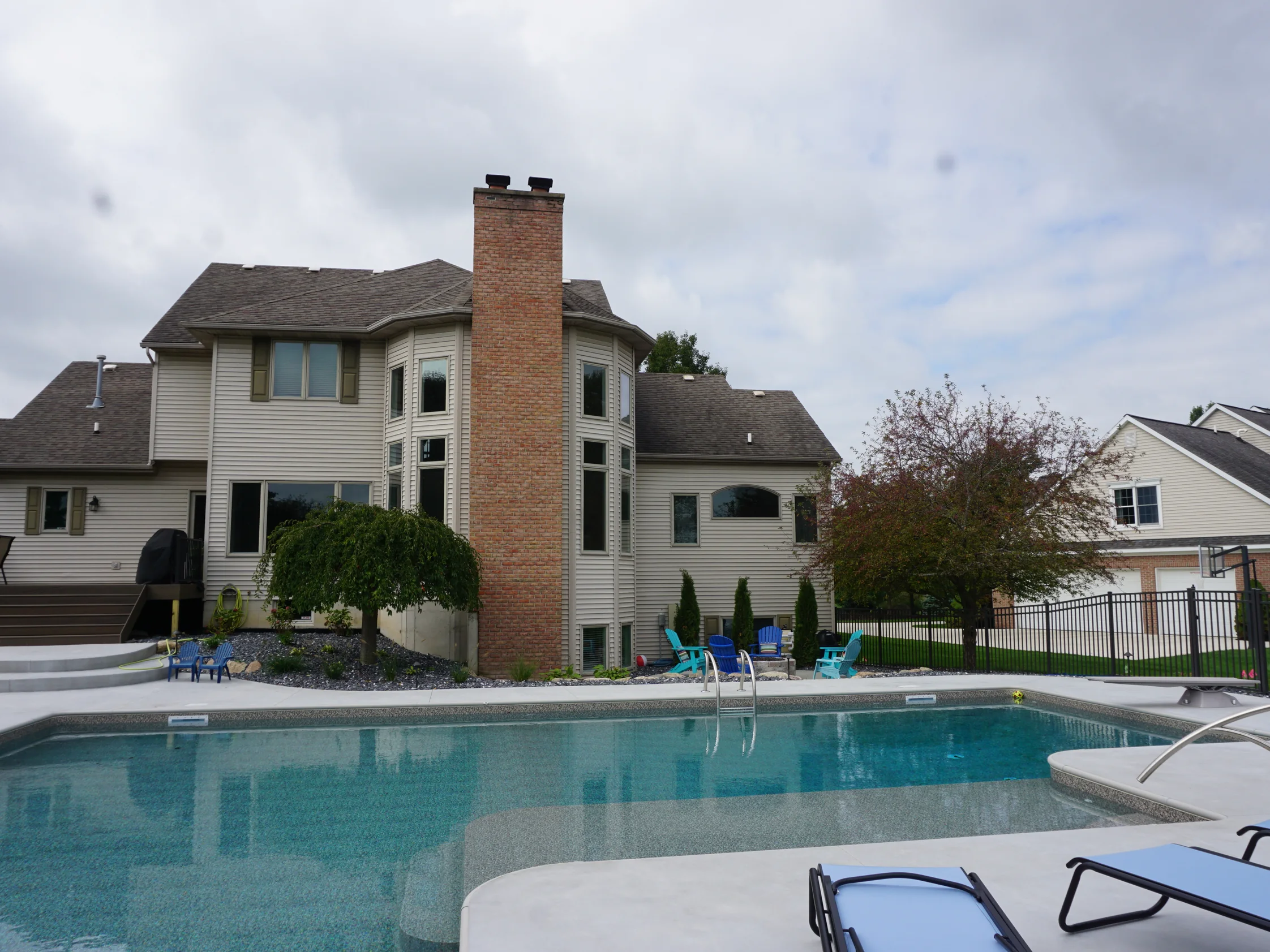 The back of the two-story house in 2019, the chimney rising the full height of the elevation past the pool and the deck