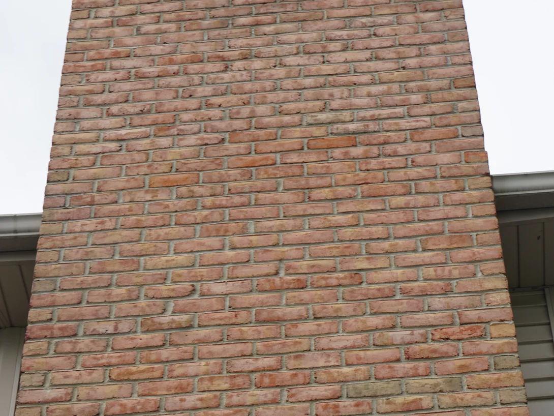 The chimney shaft filling the frame in 2019, every course reading as the same range of red, tan and cream units