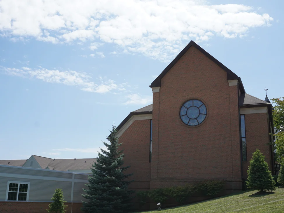 The church seen from the lawn in 2019, the main wall and the gable end reading as one even red and brown range from end to end