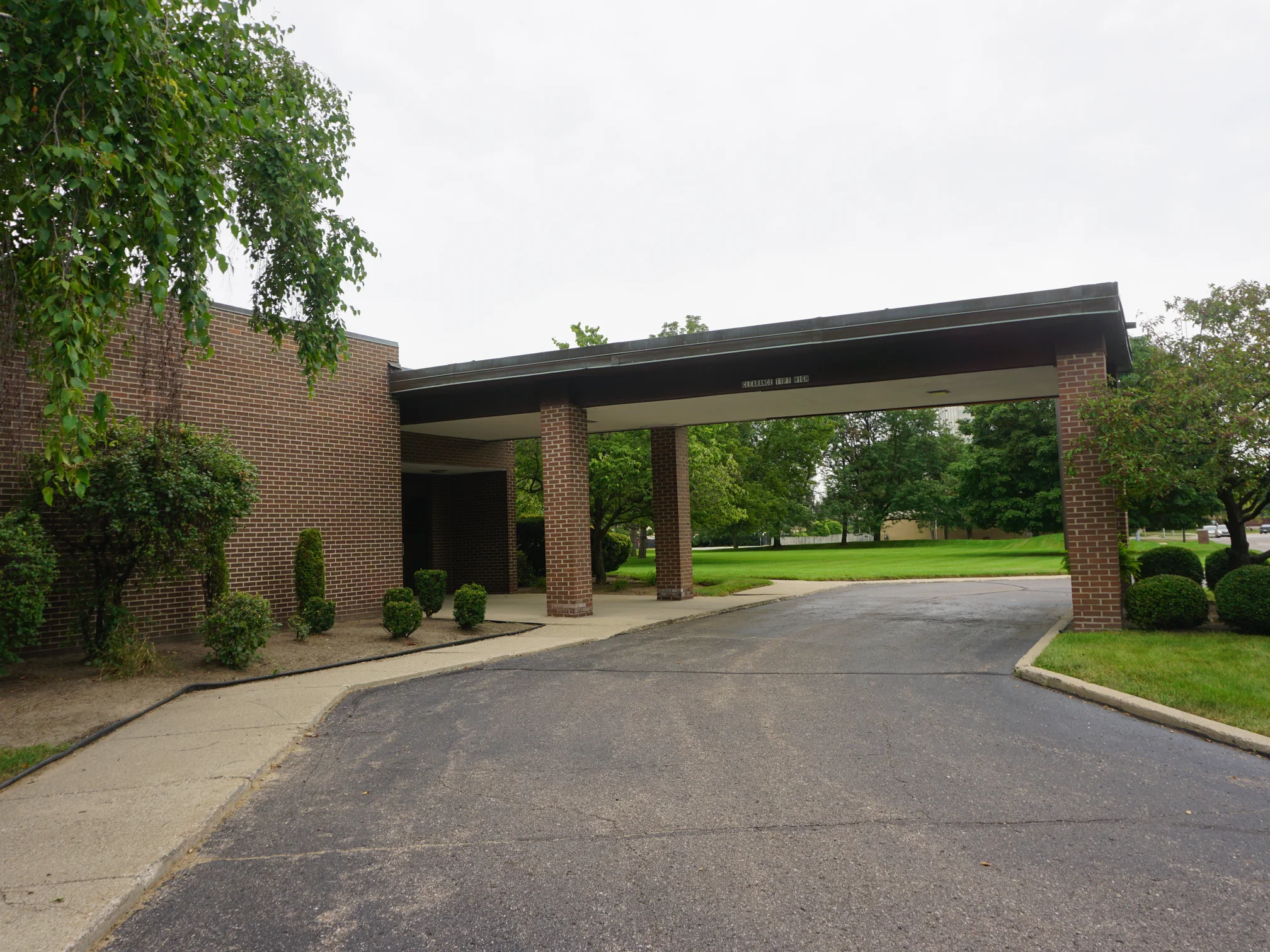 The drive-through entrance canopy from the driveway in 2019, its brick columns reading with the walls behind them as one blend