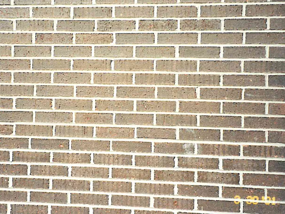Close view of the stained brick in 2001, the units running through brown, grey and dull red against pale mortar joints, with a film date stamp in the bottom corner
