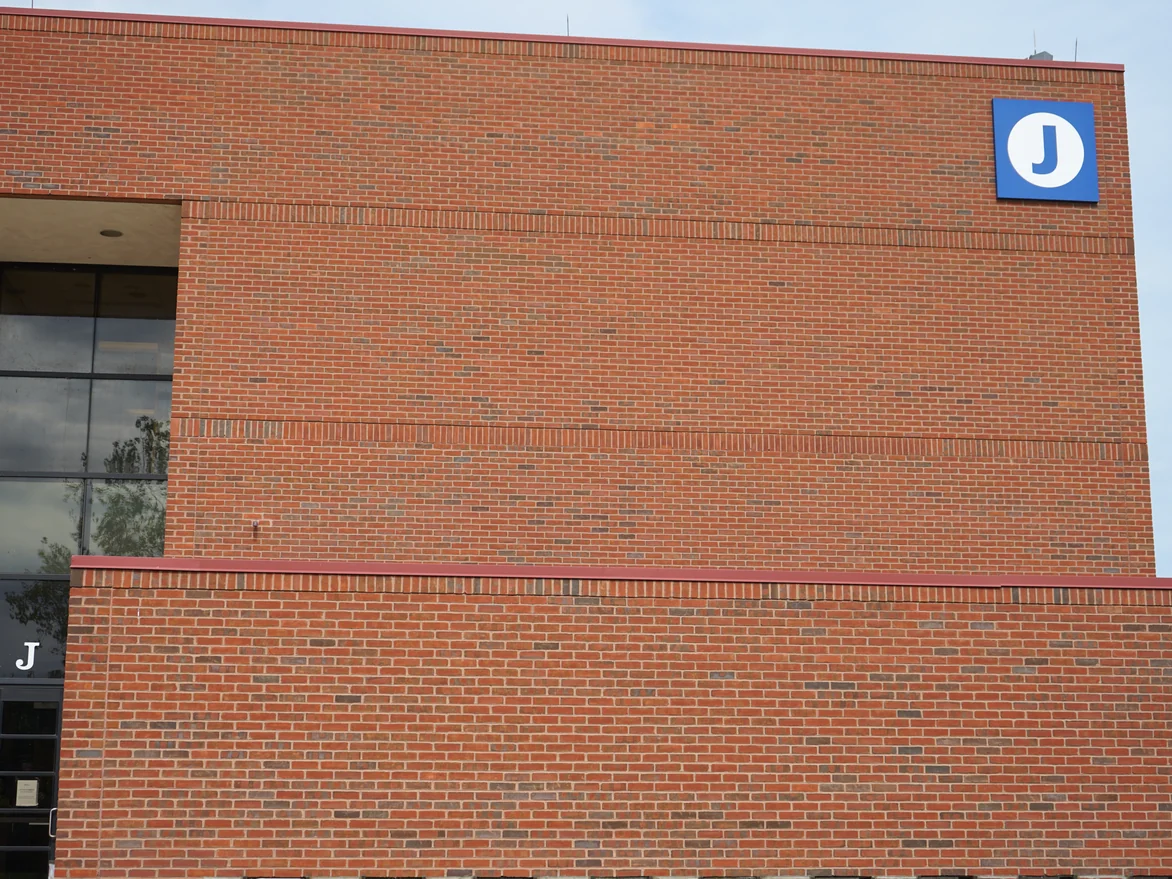 The glazed entrance bay in 2019 with the letter J on the transom, set between two heights of red brick with soldier courses running across both