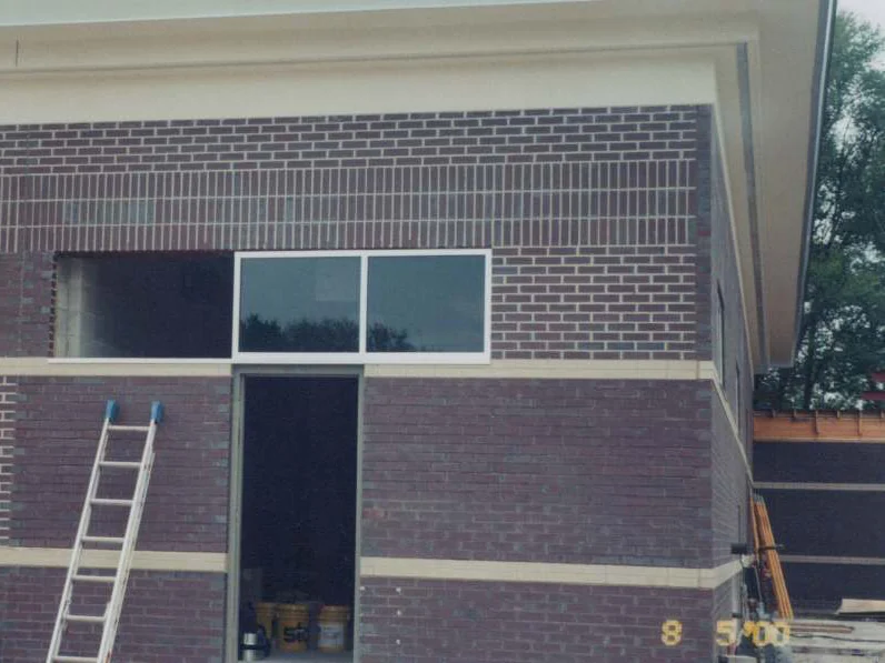 The rear wall of the building in August 2000, dark brown brick with pale mortar joints reading as bright lines around a window and an open doorway, an extension ladder against the wall and a camera date of 8 5 00 in the corner