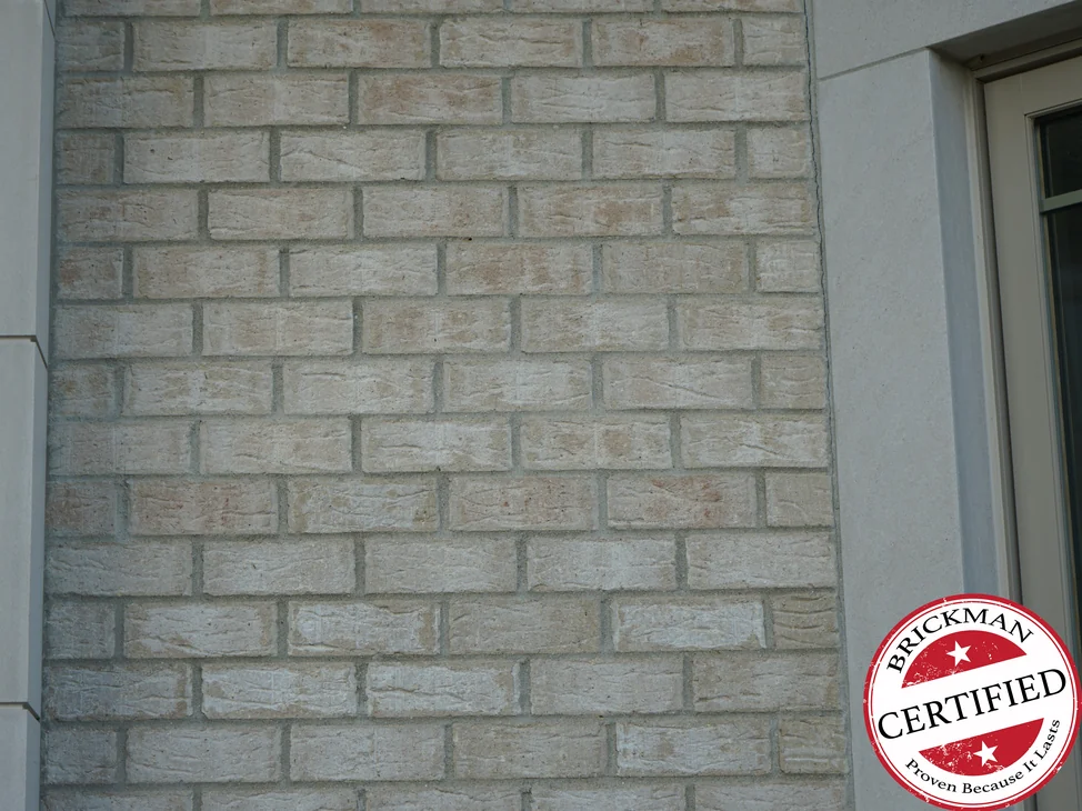 The brick between two limestone returns in 2019, an even pale cream range with faint tan through it, and a Brickman Certified stamp printed over the lower right of the frame.