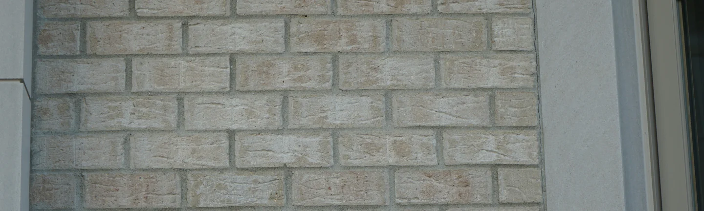 A wall of the Michigan house in 2019, pale cream brick running as one range across every course