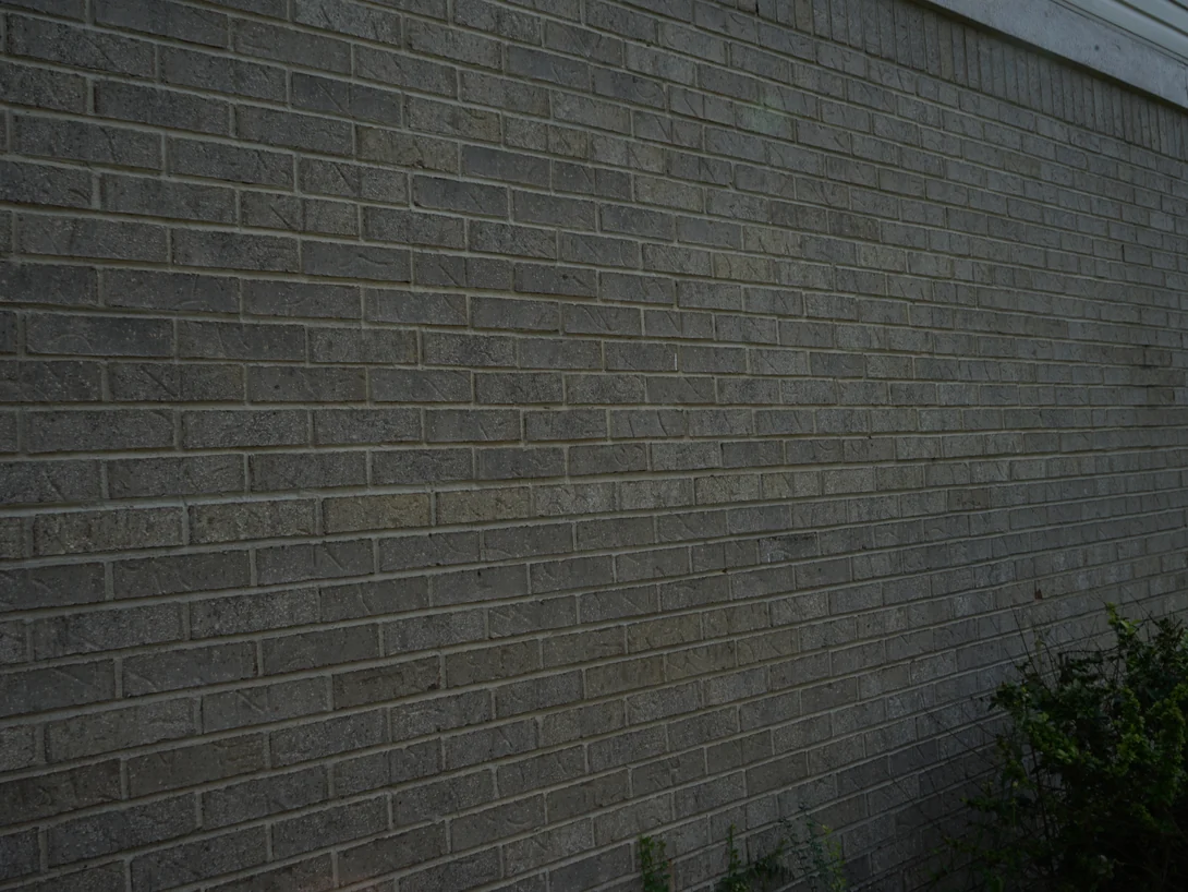 Close raking view along the brick coursing in 2019, each unit a slightly different grey inside a single range