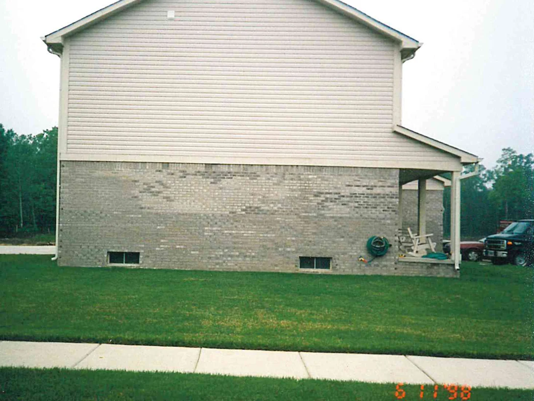 The gable end of the house in 1998, with patches of darker off-colored brick scattered across the grey wall under the siding