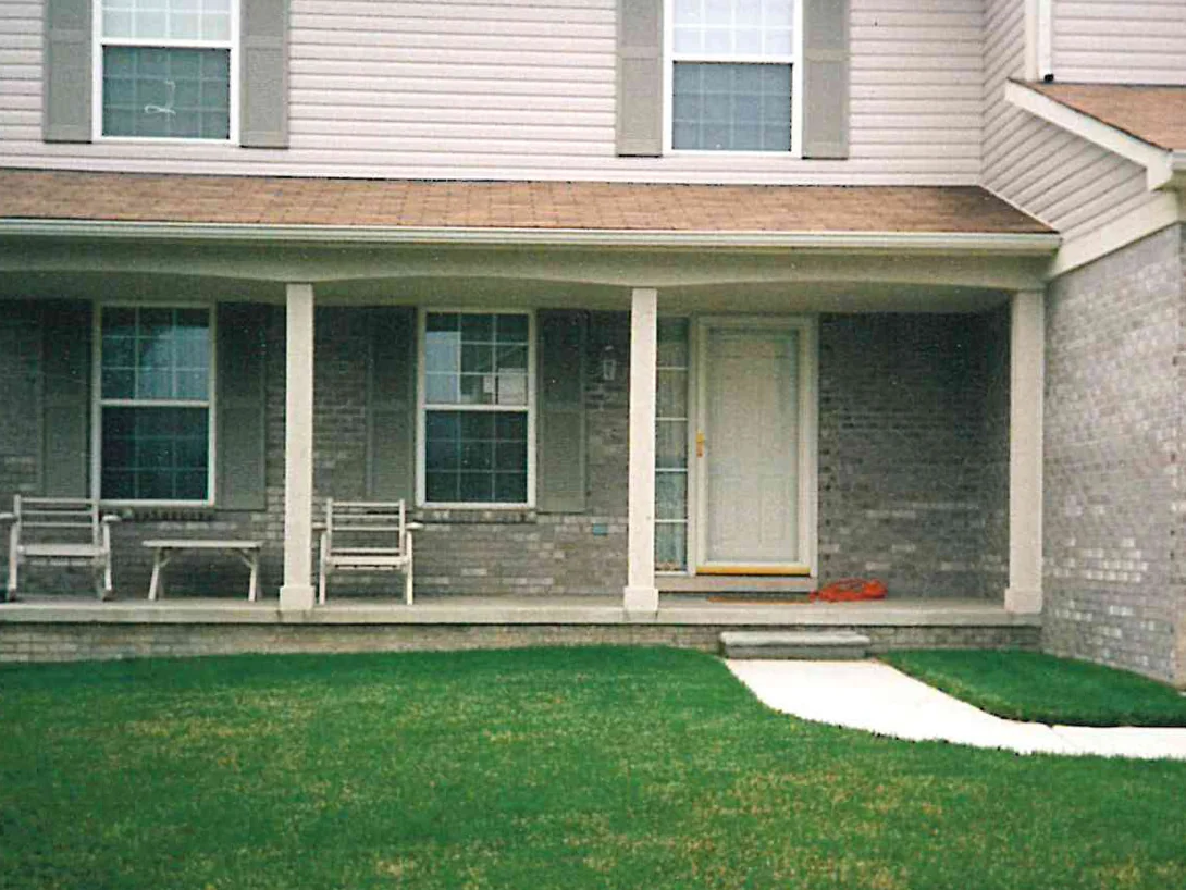 The covered front porch in 1998, grey brick between the columns and under the windows, with two rocking chairs on the deck
