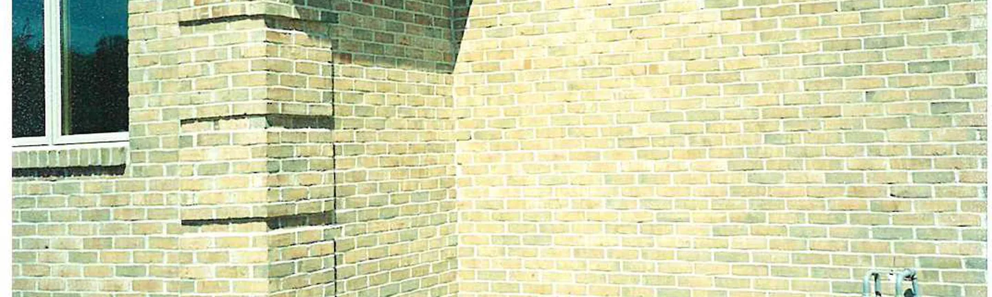 An outside corner of the Michigan house in 2003 after the light brick were darkened, buff and tan brick running to a window at the left