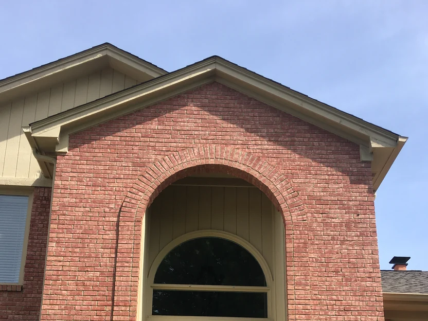 The entrance gable in 2019 at close range, a soldier-course brick arch over a half-round transom window, the salmon range even across the face