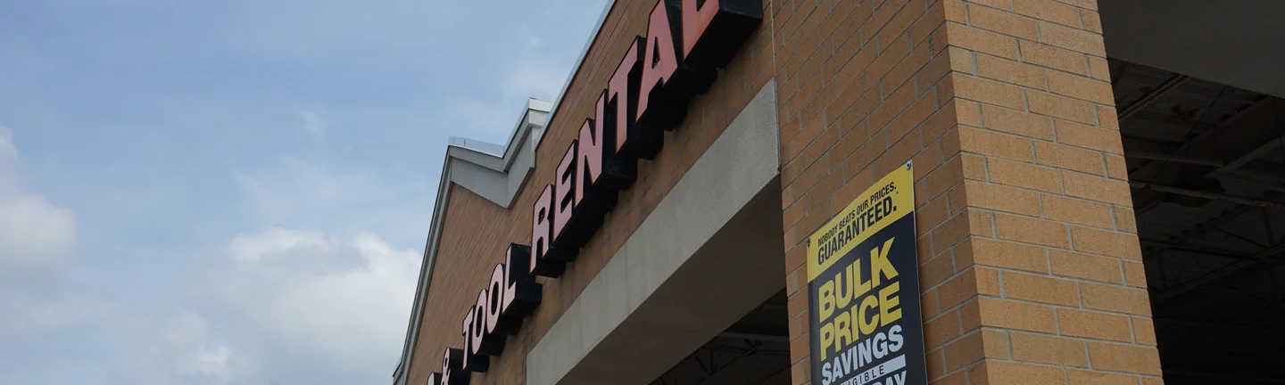The store's sign band and tan brick piers in 2019, the brick reading as one even range under the canopy
