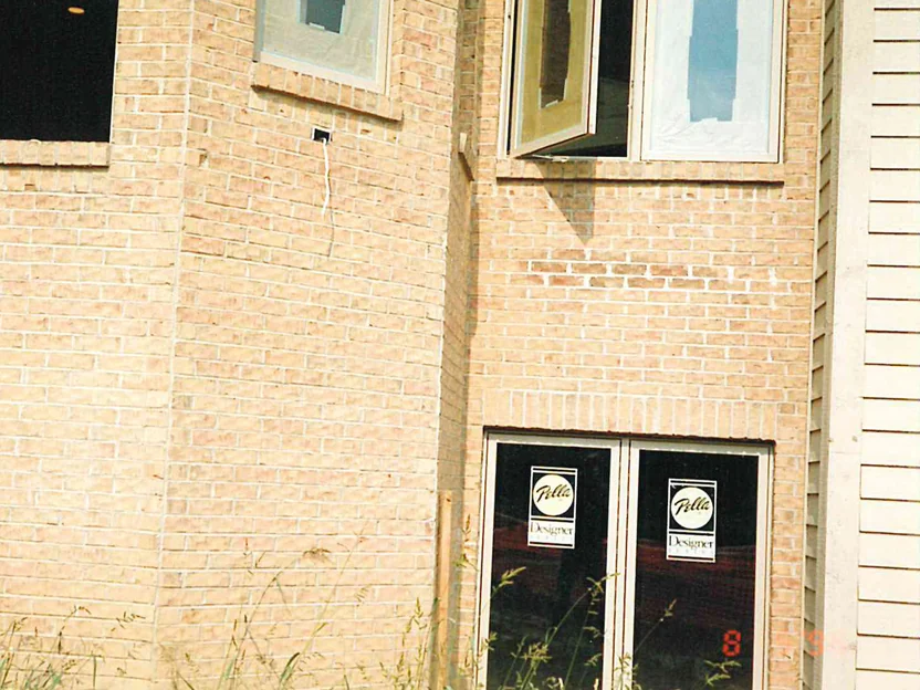 A two-story brick wall in 1996, the units a pale washed out cream and tan with patchy lighter areas, windows still carrying their maker's labels