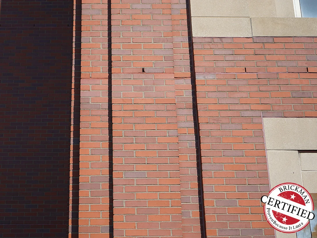 The same brick piers in 2019, the stained repair band sitting in the range of the brick around it, with the certification stamp at the lower corner