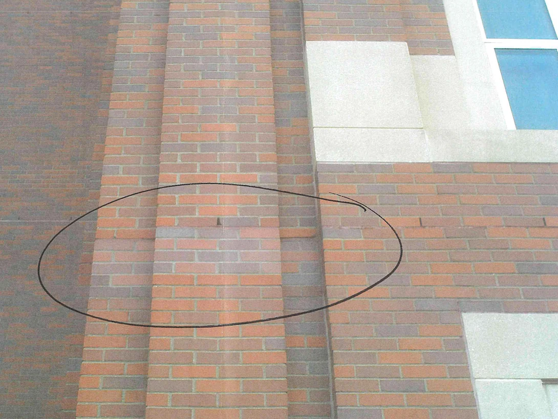 Brick piers on the hospital in 2008, with a marker circle drawn around a band of replacement brick that reads lighter than the wall around it