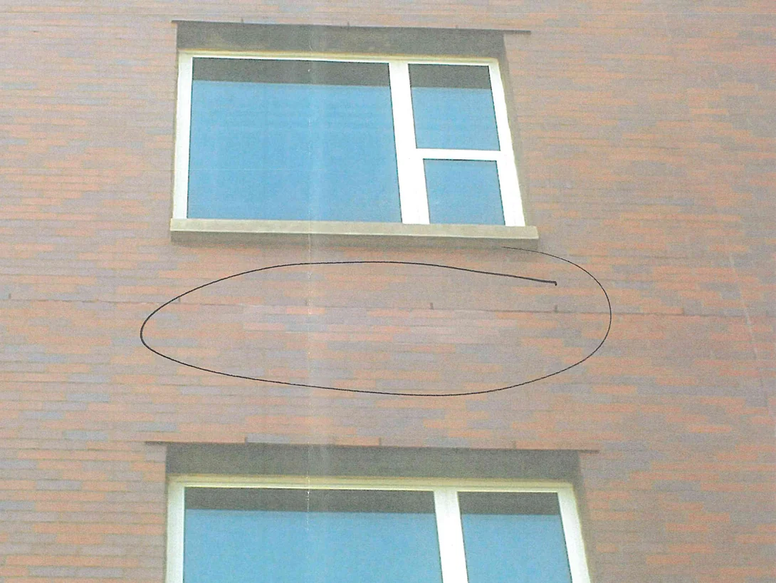 A stretch of hospital wall between two windows in 2008, a marker circle around a course of replacement brick that does not agree with its surroundings