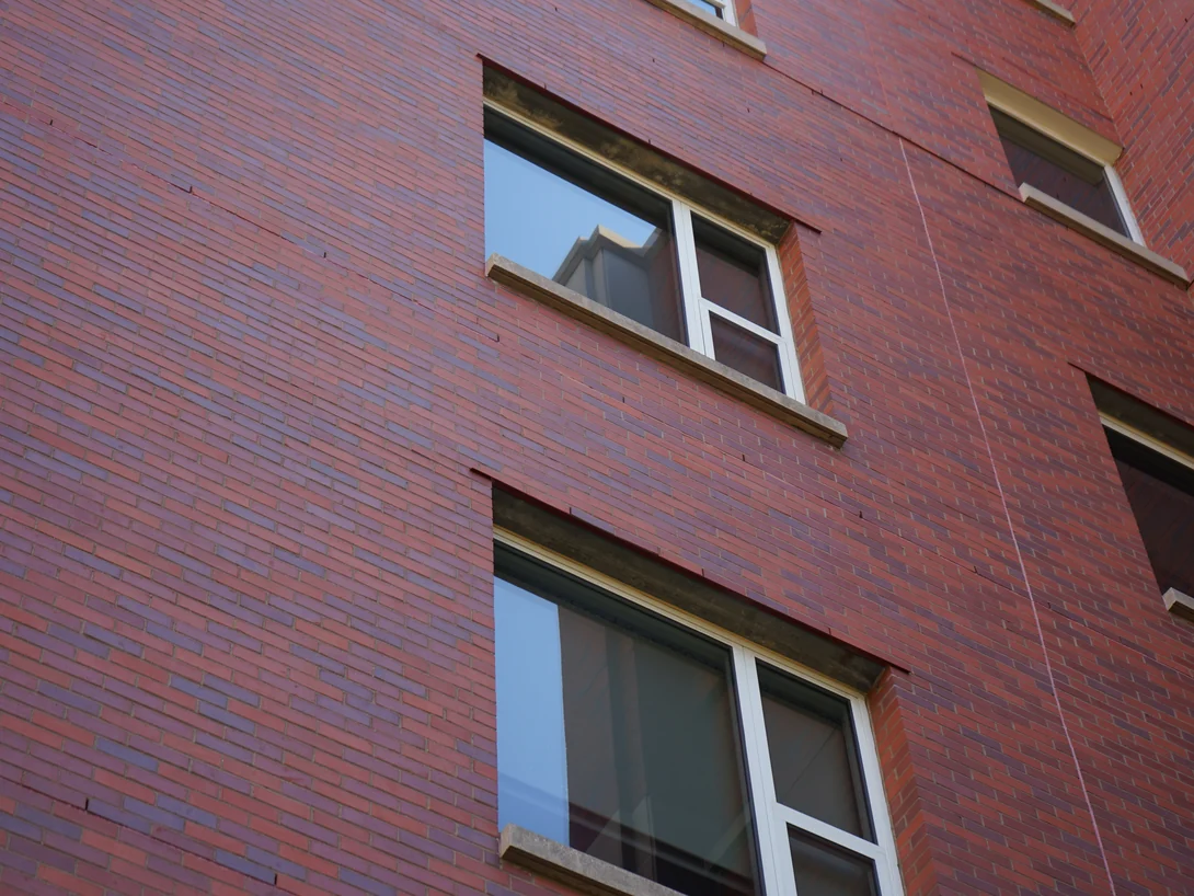 Two windows set in the hospital's brickwork in 2019, cast stone sills and heads against a wall of red and purple brick