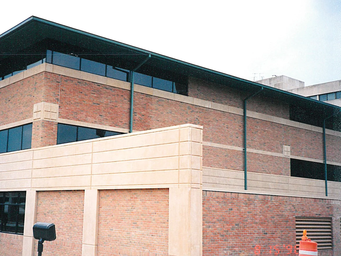 The corner of the hospital in 1998, brick above and below a cream precast screen wall, the units running from pale tan to dark red through the courses
