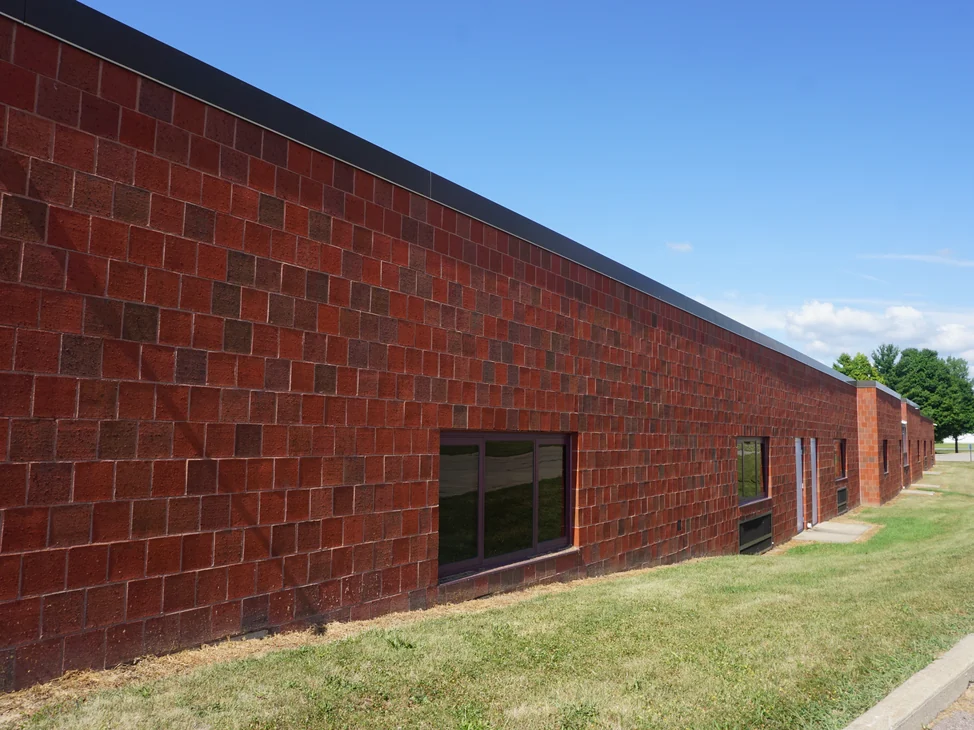 The long wall of the middle school addition in 2019, red brick with darker units scattered through it, running past a set of windows toward the original building