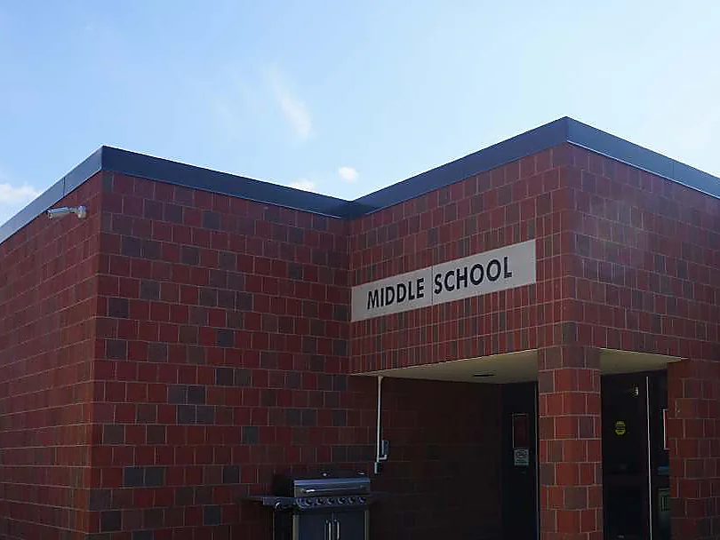 Looking up at the corner of the addition in 2019 beside the MIDDLE SCHOOL sign, the brick of the new wing and the entrance bay reading as one range