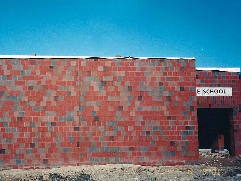 The new wing in June 2001 as laid, square units in a mix of red, grey and tan under a white cap, with the existing entrance and its SCHOOL sign beyond