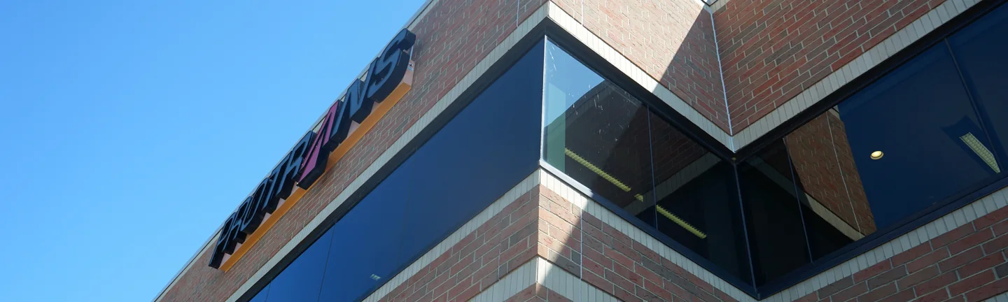 An outside corner of the office in 2019, the blended brick running as one range across both faces under a clear sky
