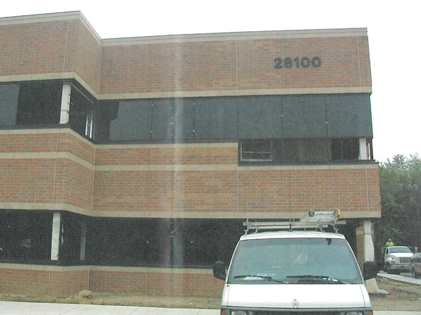 A two-story office elevation in 2003, its brick running through mismatched tan, orange and pink units across every course