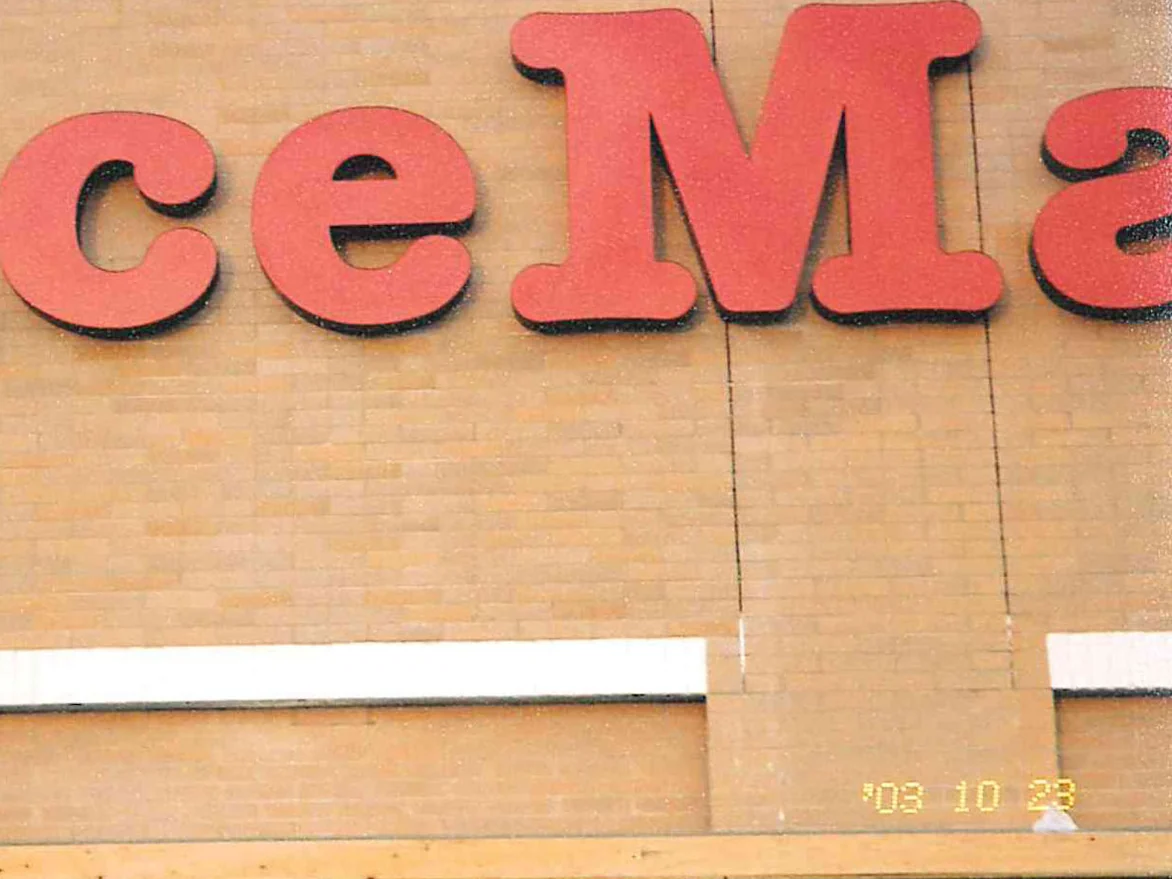 Close view of the store's concrete block wall in 2003, the block mottled and streaked darker in patches below the sign letters