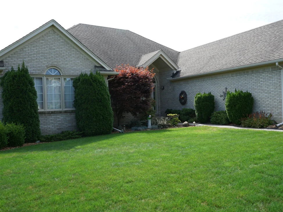 The house seen across the front lawn in 2019, its cream brick reading as one even range along the gables and the garage wing.