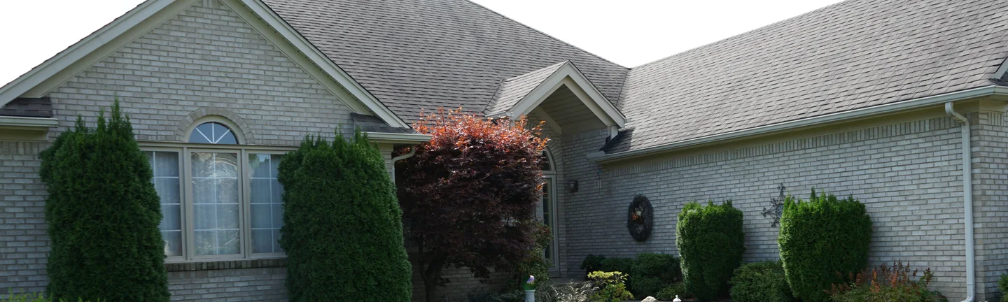 The front of the ranch house in 2019, its cream brick reading as one even range across the gables and the garage wing