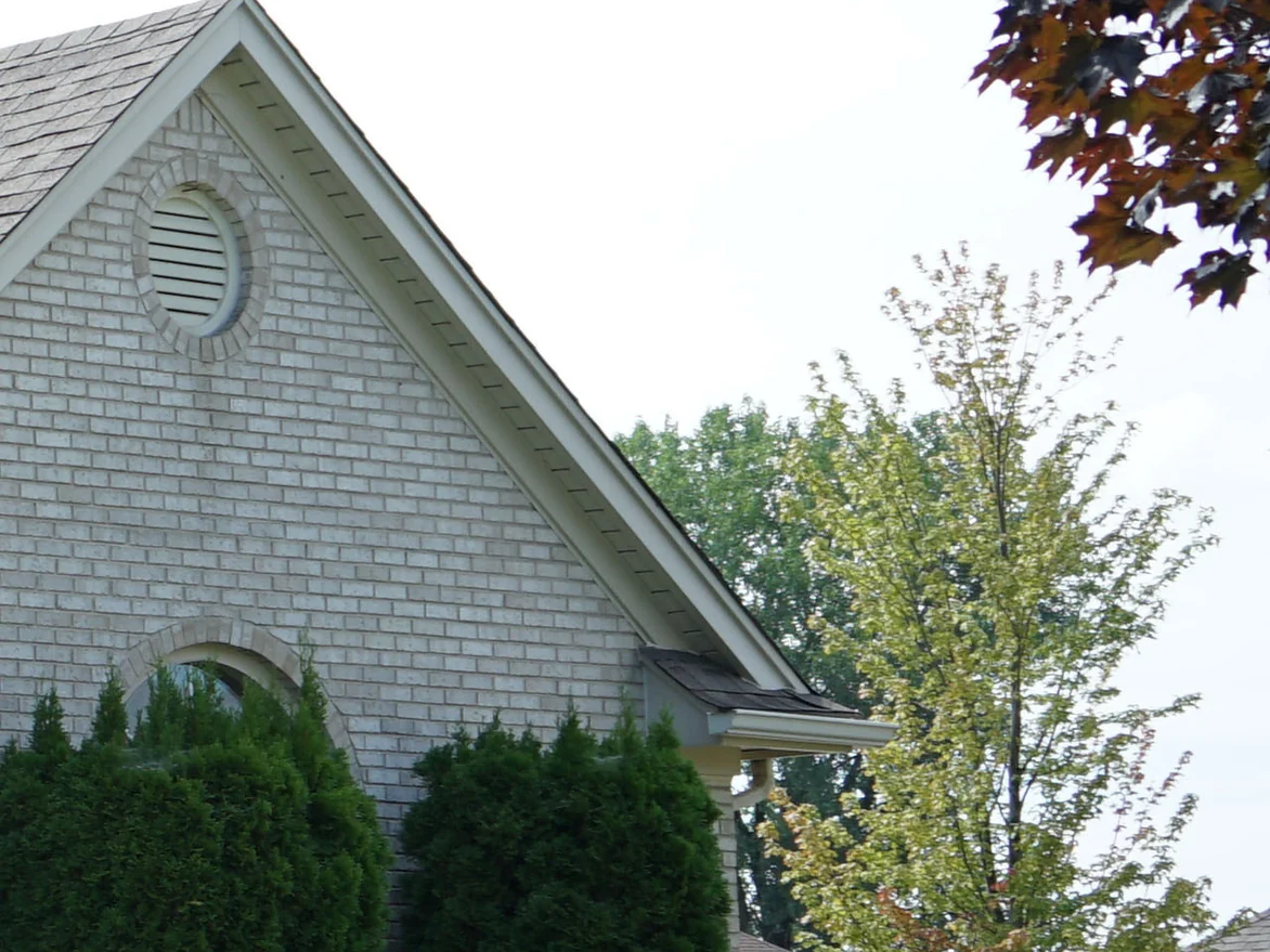 The gable end of the garage wing in 2019, an oval louver set in a brick surround above an arched window head