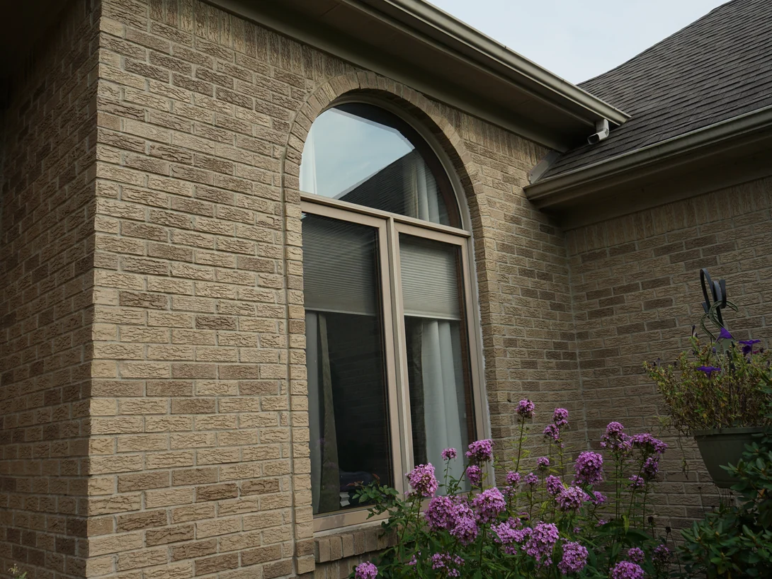 A round-headed window with a brick arch over it in 2019, the rock-faced brick around it reading as one tan and brown range