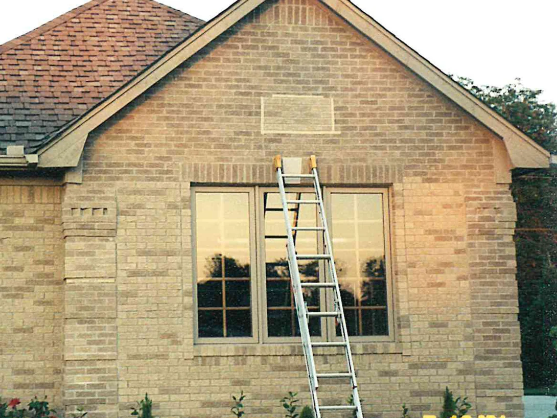 The gable end of the house in 2001 with an extension ladder against the wall, the brick a pale buff under a brown shingle roof