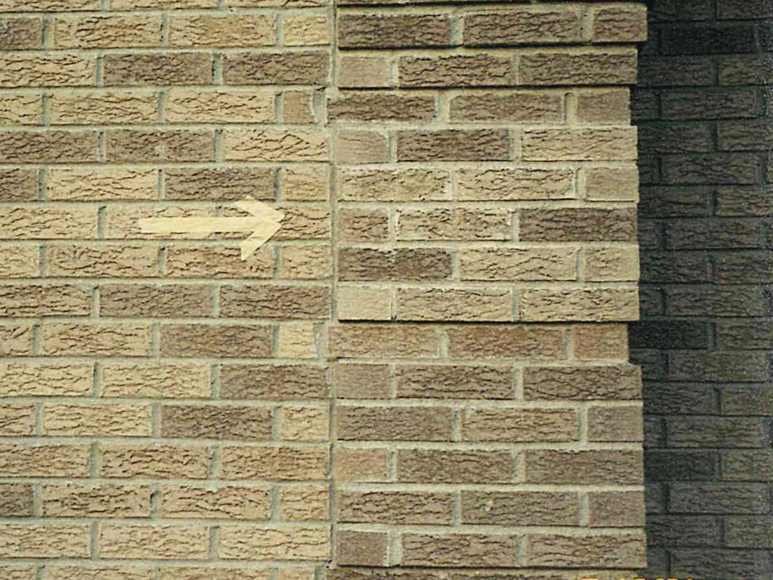Close view of the wall at a projecting brick pier in 2001, a drawn arrow marking a run of pale units among darker tan ones