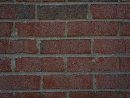 Close view of a deep red brown brick wall, the units an even color across grey mortar joints