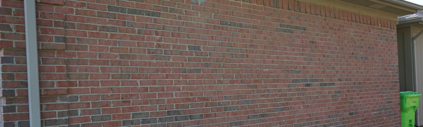 A long brick wall of the Michigan ranch house in 2019, its color even along the full run under a low hipped roof