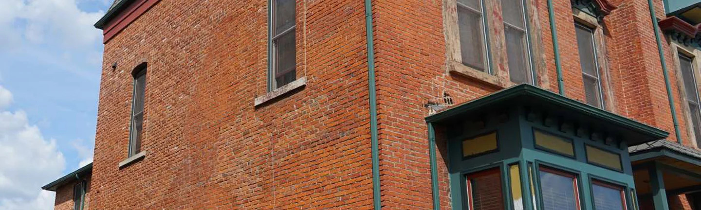 The corner of the Michigan home in 2019, one even range of red brick running round from the plain side wall onto the front bays