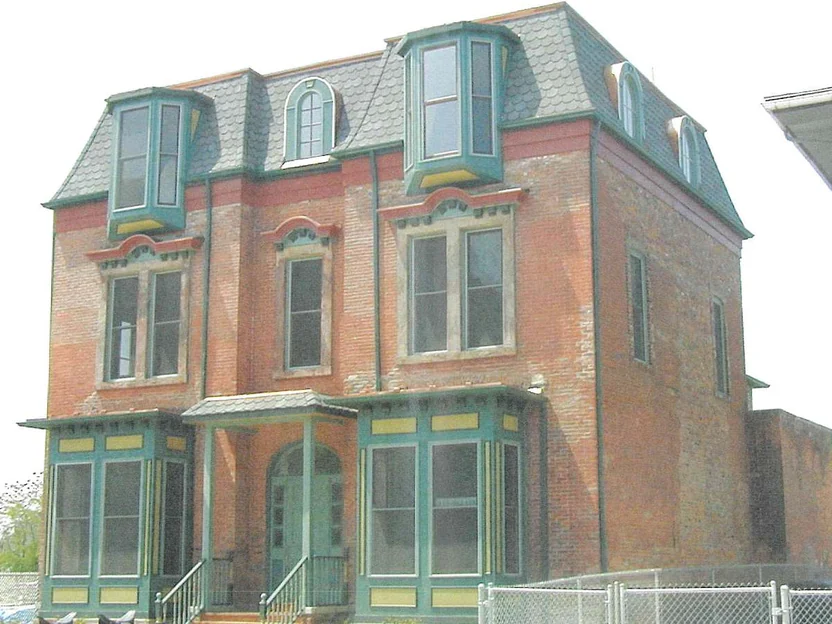 The front of the home in 2002 before staining, pink, tan and grey brick patched through the red around the windows, and a paler mottled range again on the side wall to the right