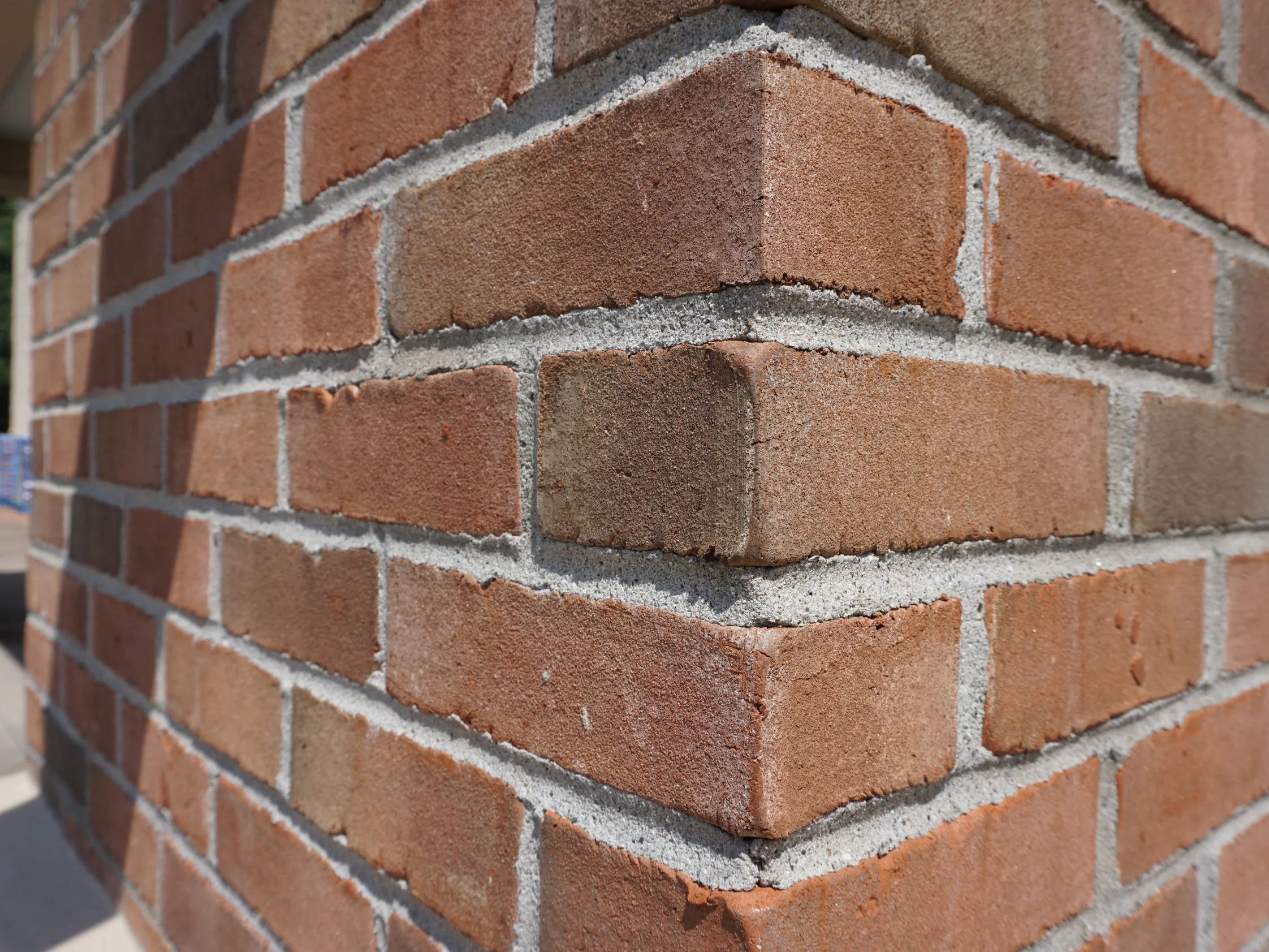 An outside corner of an entrance column in 2019, its units a blend of red, brown and tan across pale grey mortar joints
