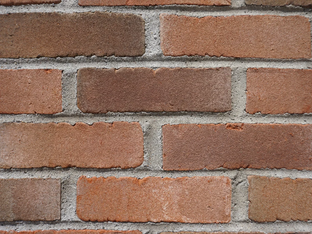 Close view of the stained brick at unit scale in 2019, the units ranging from orange red through tan to dark brown across grey mortar