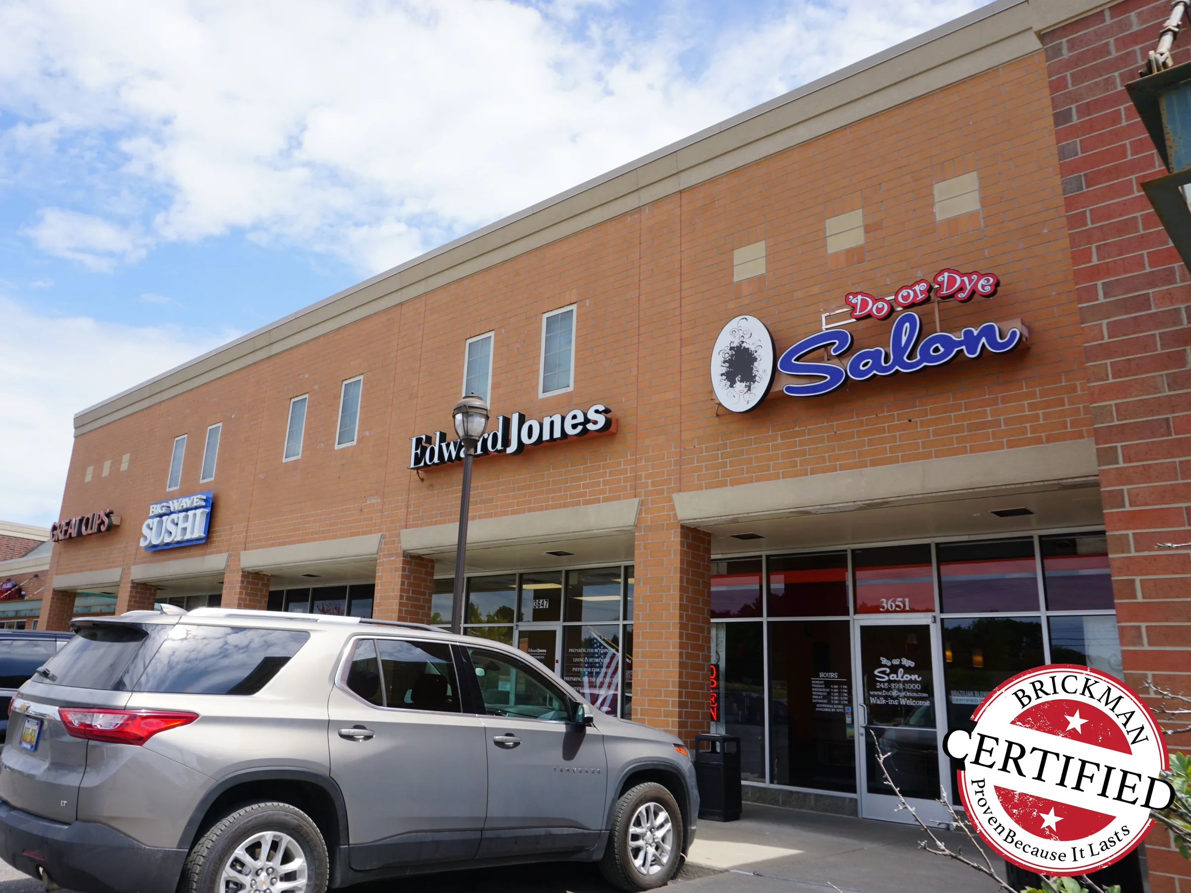 The same elevation looked along in 2019, the upper wall and the storefront brick reading as one range from the near pier to the far end of the block, the frame carrying the Brickman Certified stamp