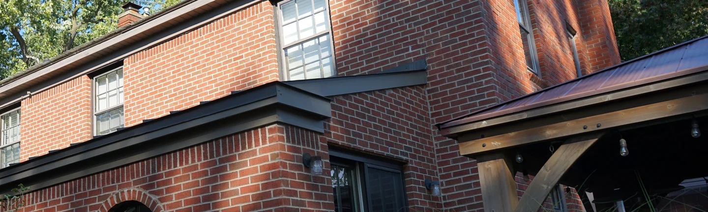 The Michigan house in 2019, its brick an even red range in summer sun above a round window set in a radial brick surround