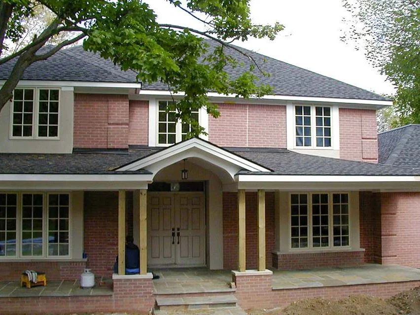 The front of the house later in 2003, every brick one salmon color from the porch base to the upper windows, the porch posts still bare wood and a propane tank on the porch floor