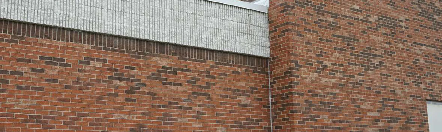 Red brick running through an outside corner of the Michigan school in 2019 under a grey masonry band