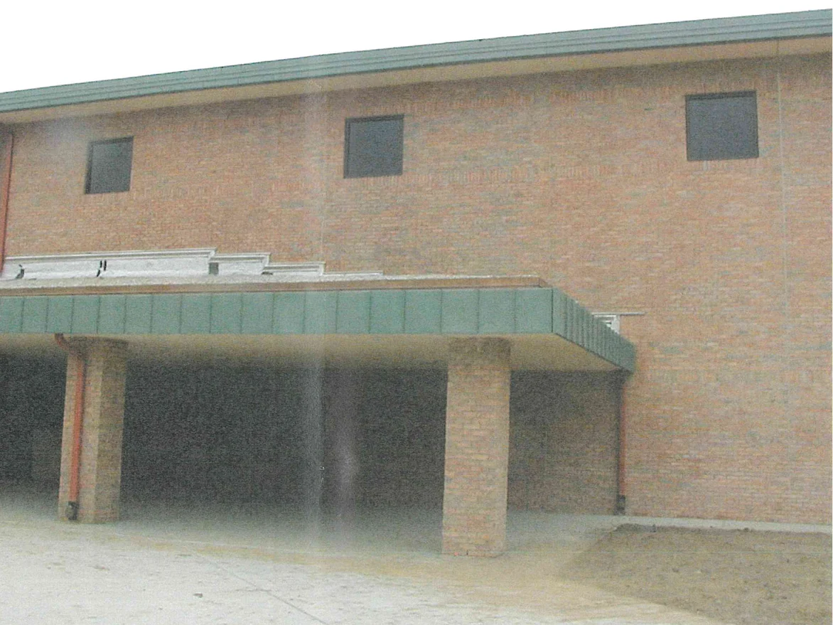 The entrance elevation in 2003 after the work, the two-story wall above the canopy reading as one even tan brick with three square windows under a shallow roof